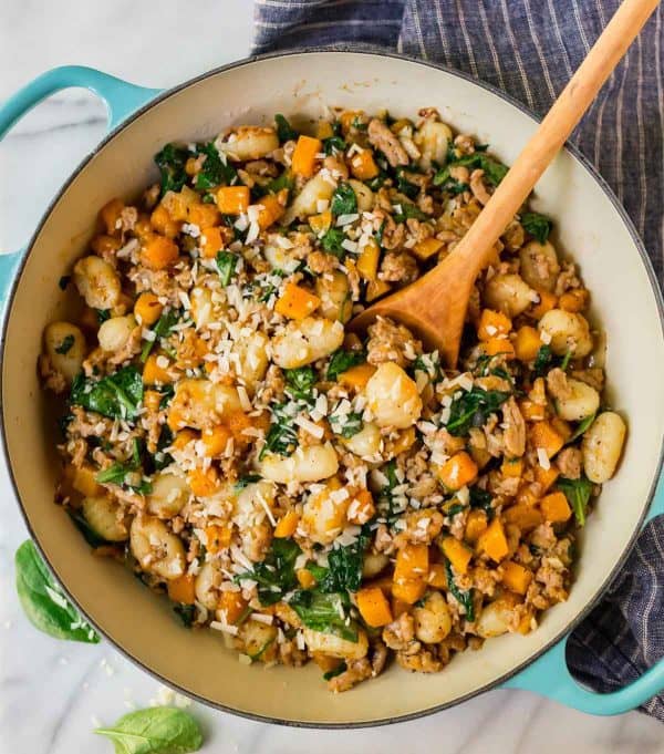 Butternut squash gnocchi in a large pot with a wooden spoon from family meal plan.