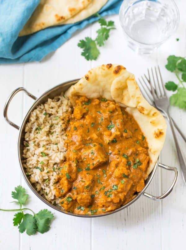 Butter chicken and brown rice in a metal dish with naan bread from family meal plan.