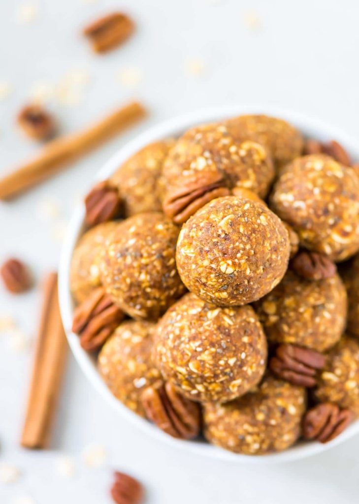 Pumpkin energy balls in a white bowl with pecans and cinnamon stick garnish from family meal plan.