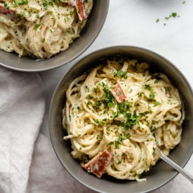 Two grey bowls filled with pasta carbonara.