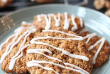 Pile of vegan carrot cake lactation cookies on a teal plate with cookies on a rack in the background.