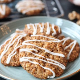 Pile of vegan carrot cake lactation cookies on a teal plate with cookies on a rack in the background.