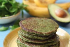 Stack of spinach and avocado green pancakes on a yellow plate.