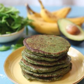 Stack of spinach and avocado green pancakes on a yellow plate.