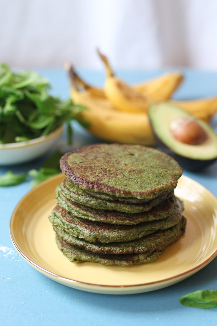 Stack of spinach and avocado green pancakes on a yellow plate.