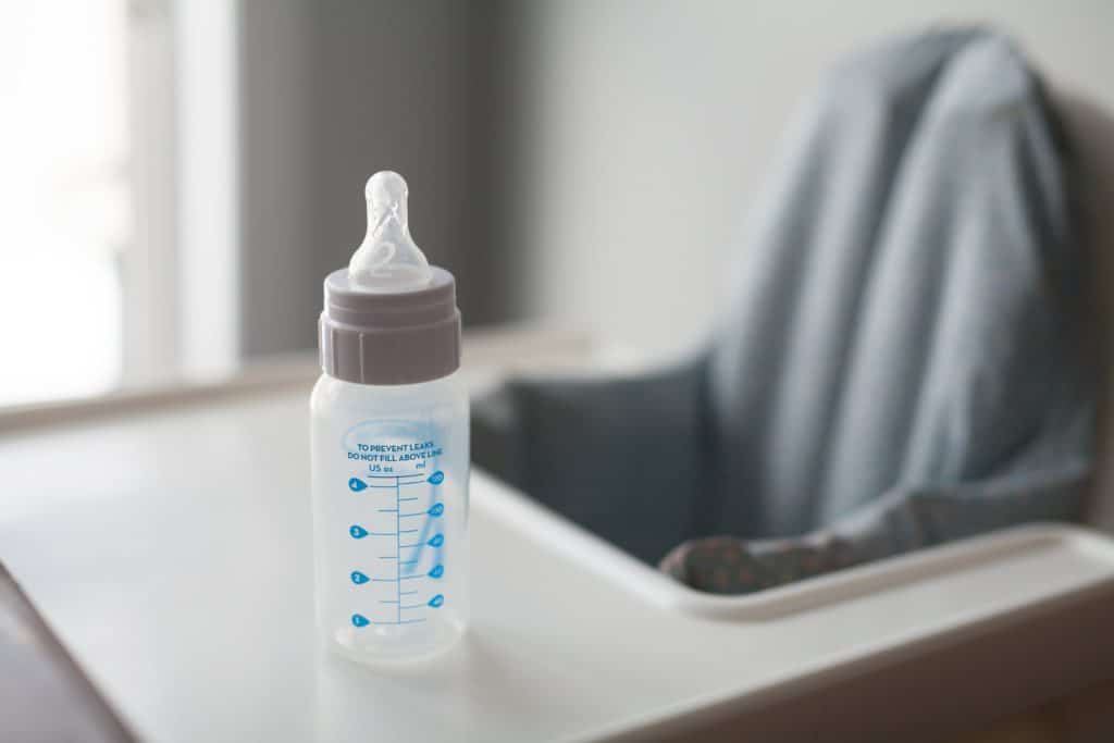Baby bottle on a high chair table.