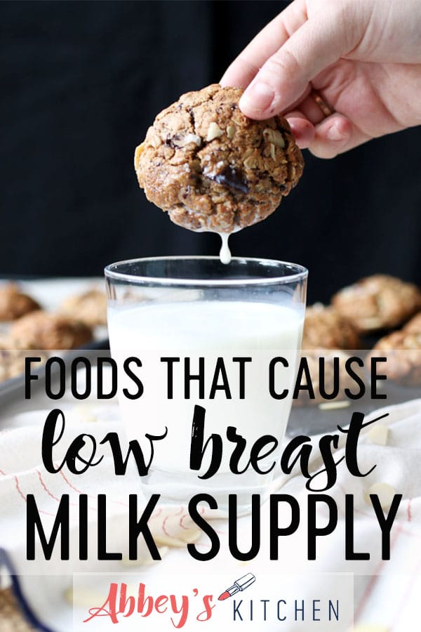 Hand dipping chocolate almond lactation cookies in a glass of milk with text overlay.