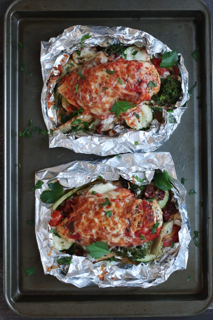Two baked chicken parm foil pack dinners on a baking sheet.