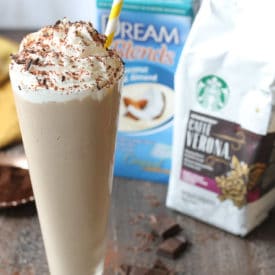 Tiramisu vegan milkshake in a tall glass with whip cream and a straw using Starbucks coffee and coconut milk.