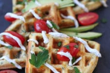 Egg and cheese savoury protein waffles topped with sliced avocados, cherry tomatoes, creamy drizzle and parsley.
