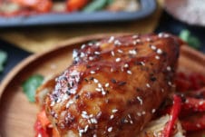 Sticky chicken breast on cabbage and peppers on a wooden plate.