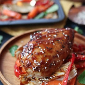 Sticky chicken breast on cabbage and peppers on a wooden plate.