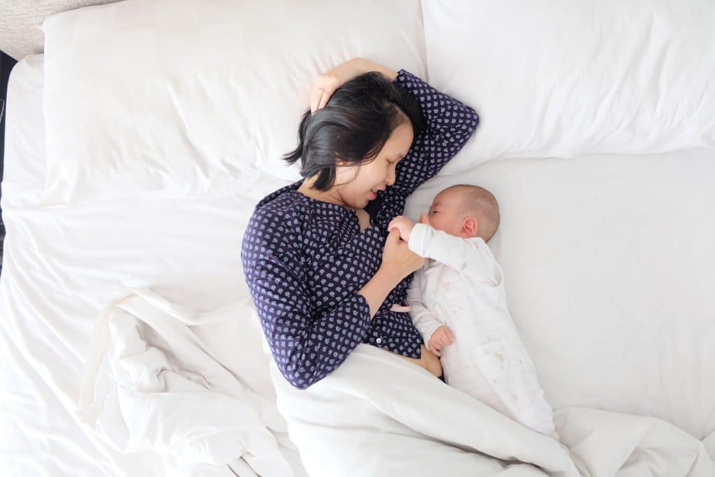 woman and her baby lying in bed together