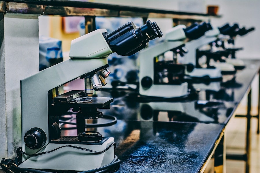 A series of microscopes on a counter in a laboratory.