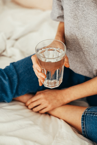 Person sitting holding a large glass of water.