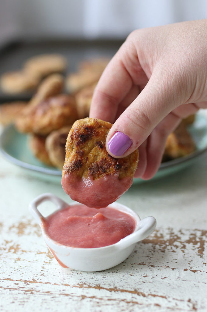 Hand dipping a chicken nugget in a fruit puree.