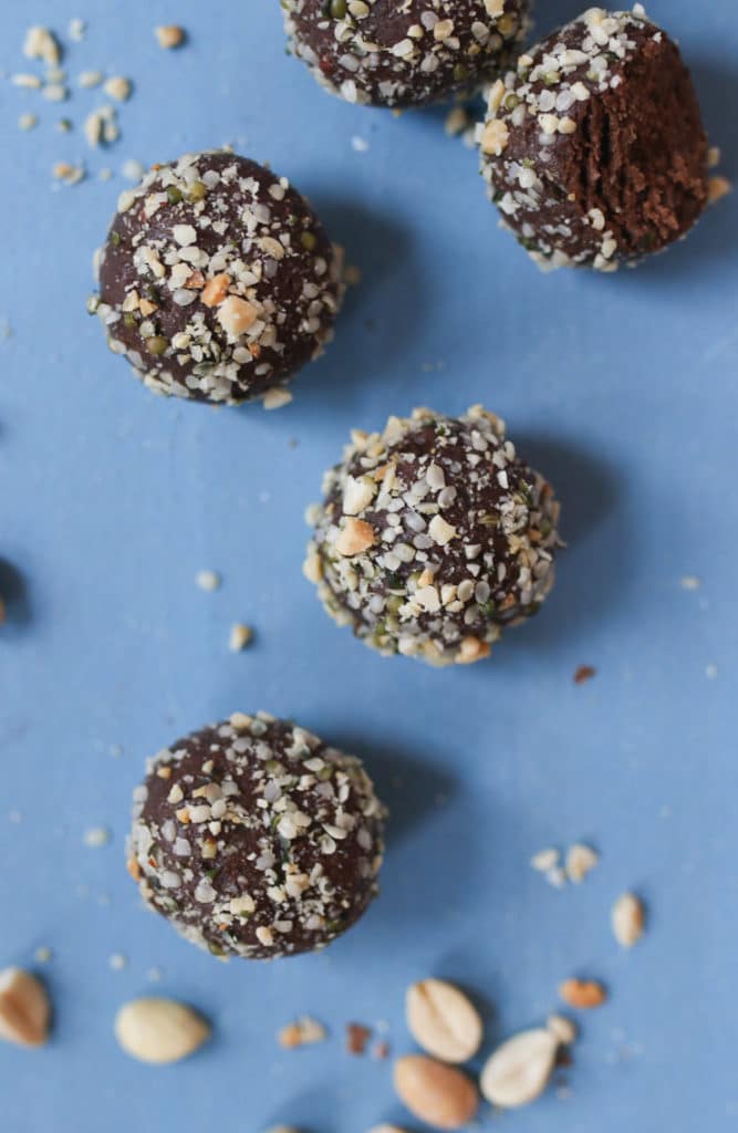 Peanut butter chocolate protein balls scattered on a blue background.