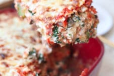 Spatula lifting a piece of vegetarian matza lasagna from a red casserole dish for Passover.