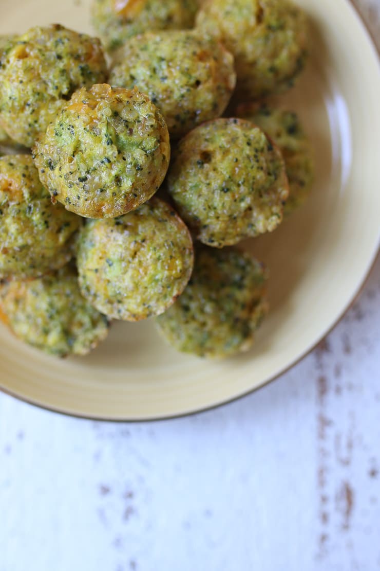 Pile of mini broccoli and cheese egg muffins on a yellow plate.