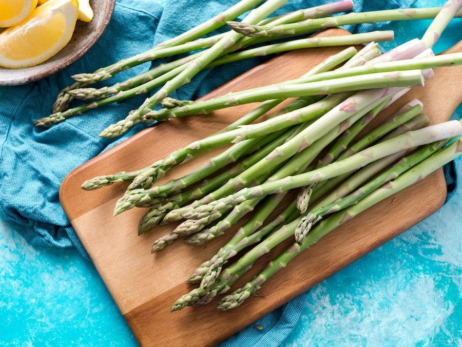 A pile of fresh asparagus on a cutting board.