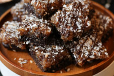 Samoa girl scout vegan brownies on a wooden plate topped with chocolate and coconut.