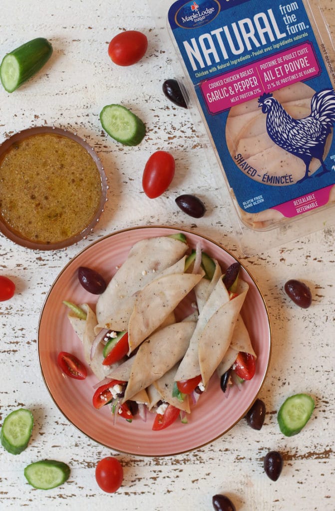 Greek style deli roll up snack on a pink plate next to oil vinegar dip.