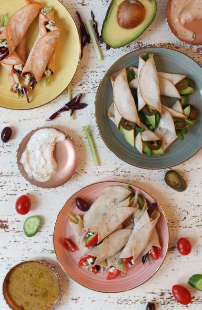 California keto deli roll up, buffalo style deli roll up and greek deli roll up on plates with dip.