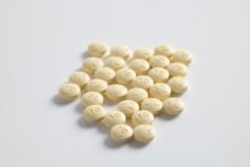 A bunch of small round pills on a white surface.
