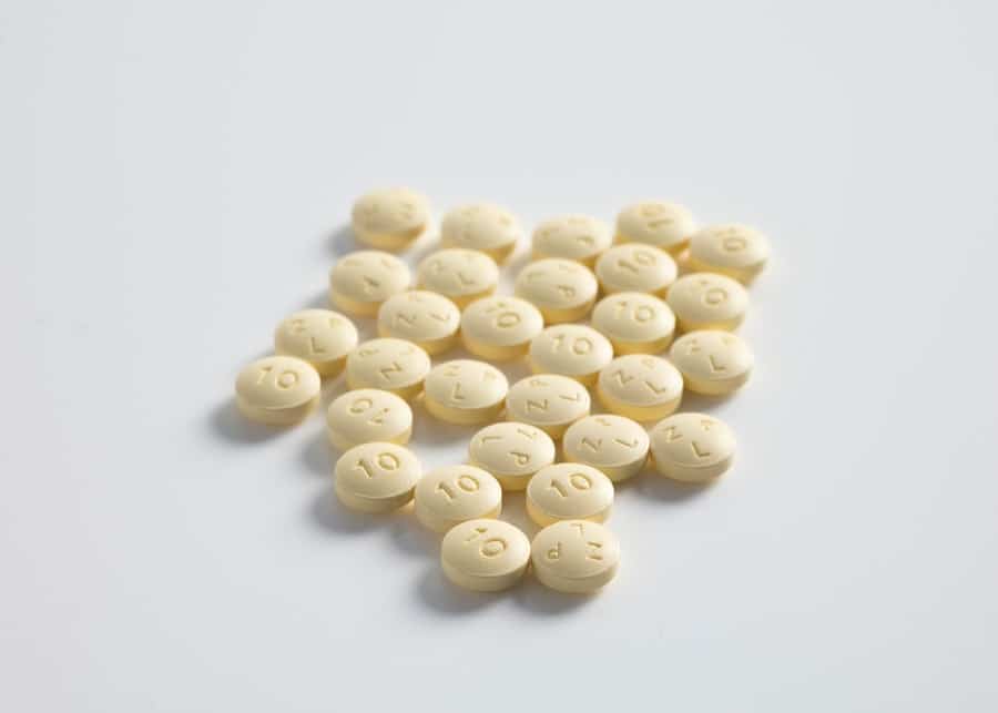 A bunch of small round pills on a white surface.