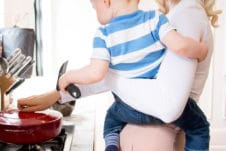 Women holding her baby while cooking.