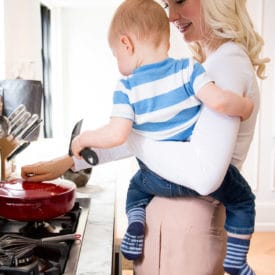Women holding her baby while cooking.
