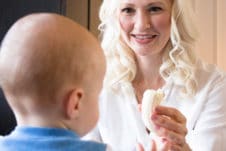 Women feeding her baby in a high chair.