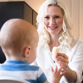 Women feeding her baby in a high chair.