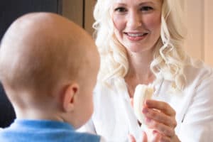 Women feeding her baby in a high chair.