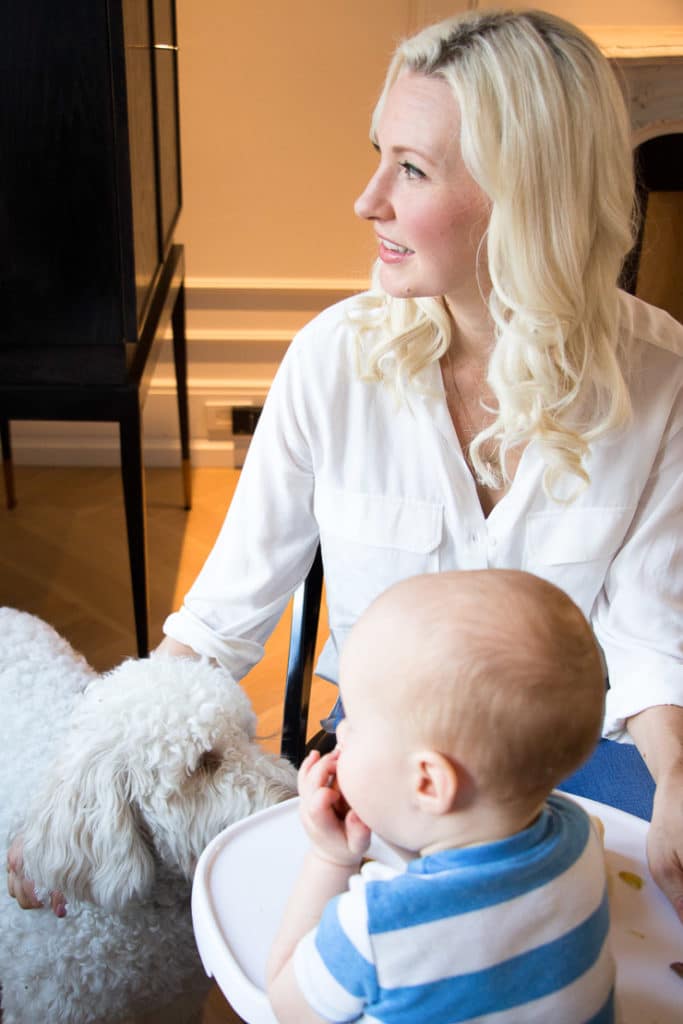 Women sitting next to her baby in a high chair and her dog.