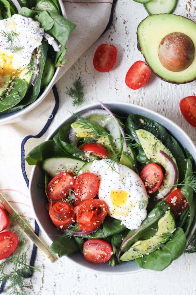 Keto salad topped with poached egg, smoked salmon and avocadoes in a bowl. 