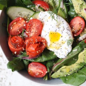 Keto salad topped with poached egg, smoked salmon and avocadoes in a bowl.