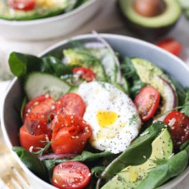 Keto salad topped with poached egg, smoked salmon and avocadoes in a bowl.