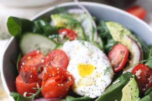 Keto salad topped with poached egg, smoked salmon and avocadoes in a bowl.
