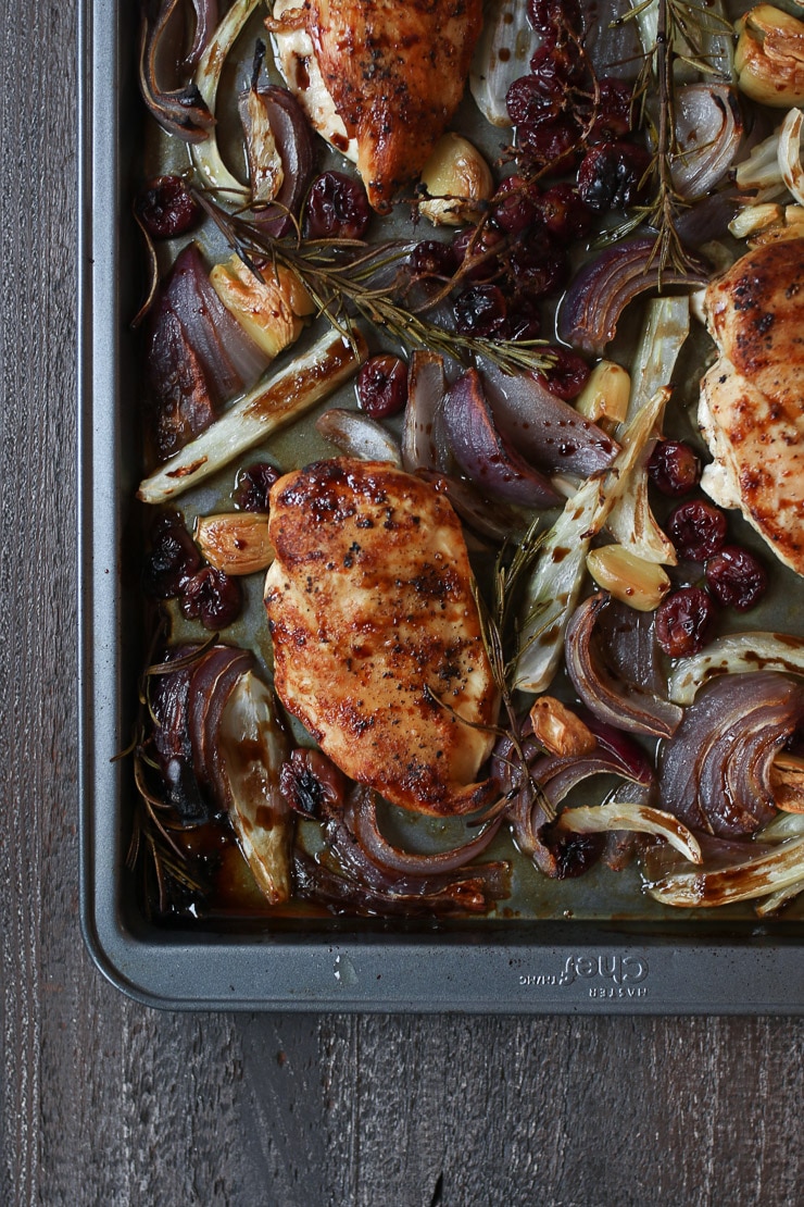 Chicken with balsamic glaze on a sheet pan with roasted grapes and veggies.