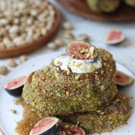 Pistachio crusted french toast on a white plate topped with yogurt and figs.