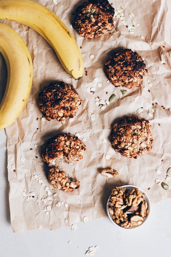 Granola cookies on brown paper next to bananas.