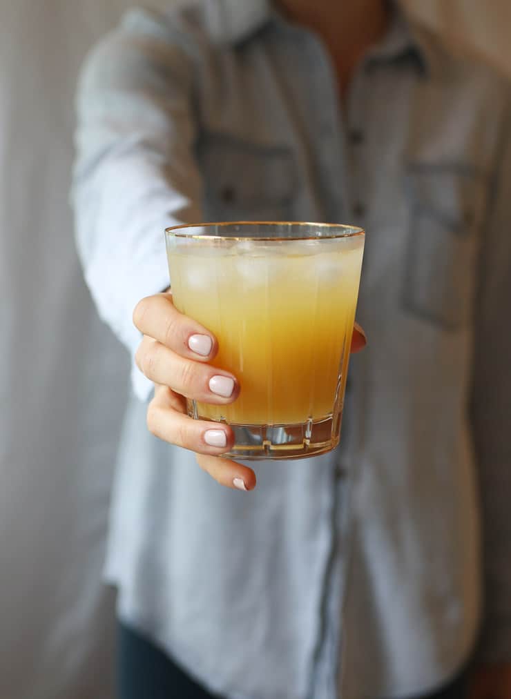 Person holding a glass of a healthy orange hydrating low sugar drink