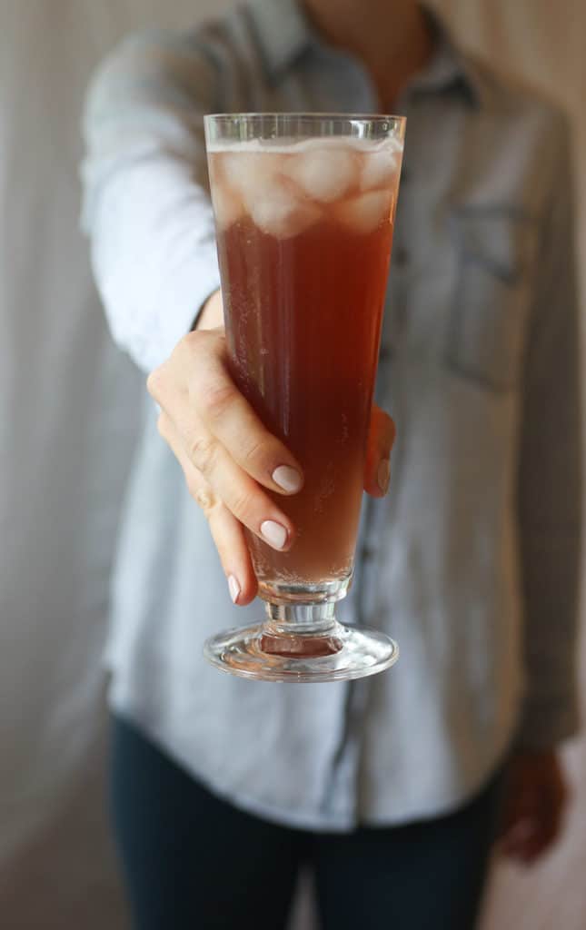 Person holding a glass of a healthy red hydrating low sugar drink