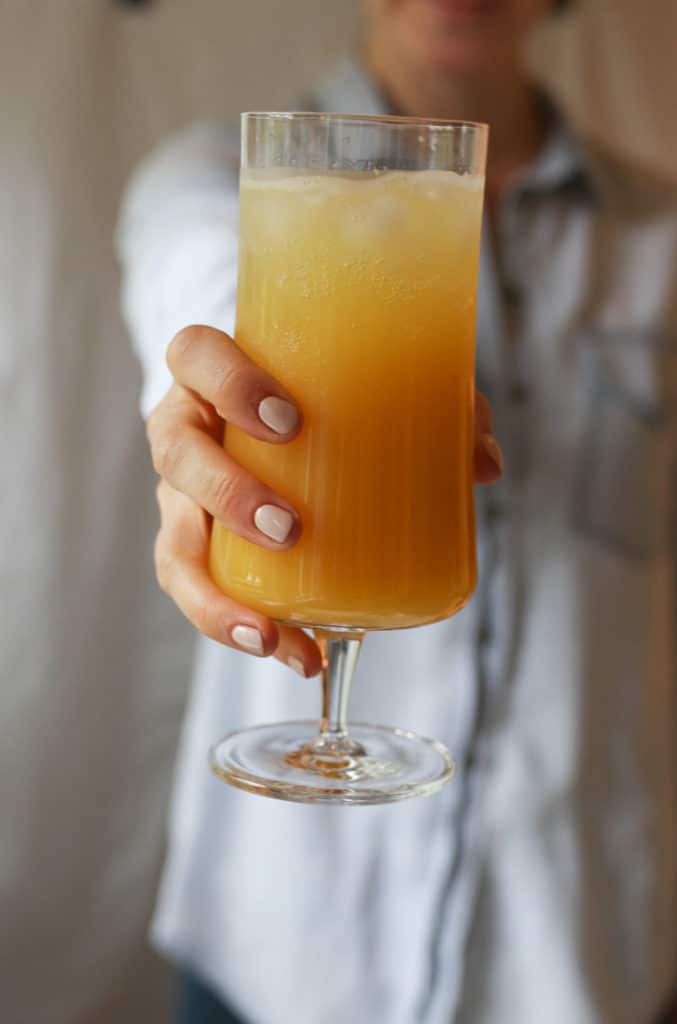 Person holding a glass of a healthy orange hydrating low sugar drink