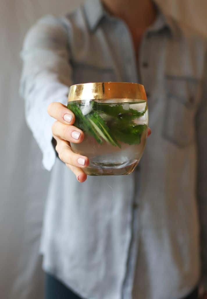 Person holding a glass of a healthy green hydrating low sugar drink.