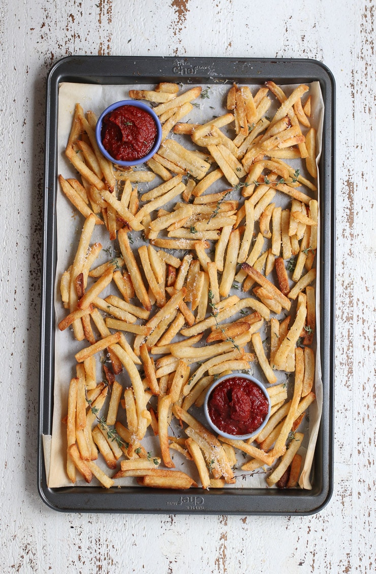 A tray of french fries with two small bowls of homemade ketchup. 