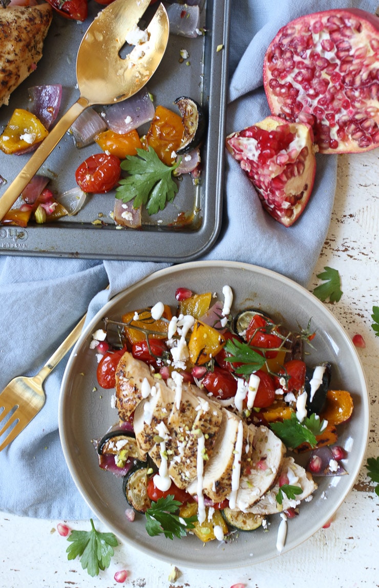 Greek chicken served on a plate with veggies and tzaziki drizzle.