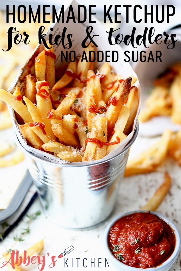 Bucket of fries with ketchup drizzle on top next to a small bowl of homemade ketchup.