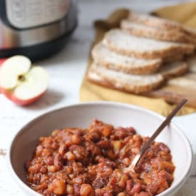 Baked beans in a bowl with a serving spoon.